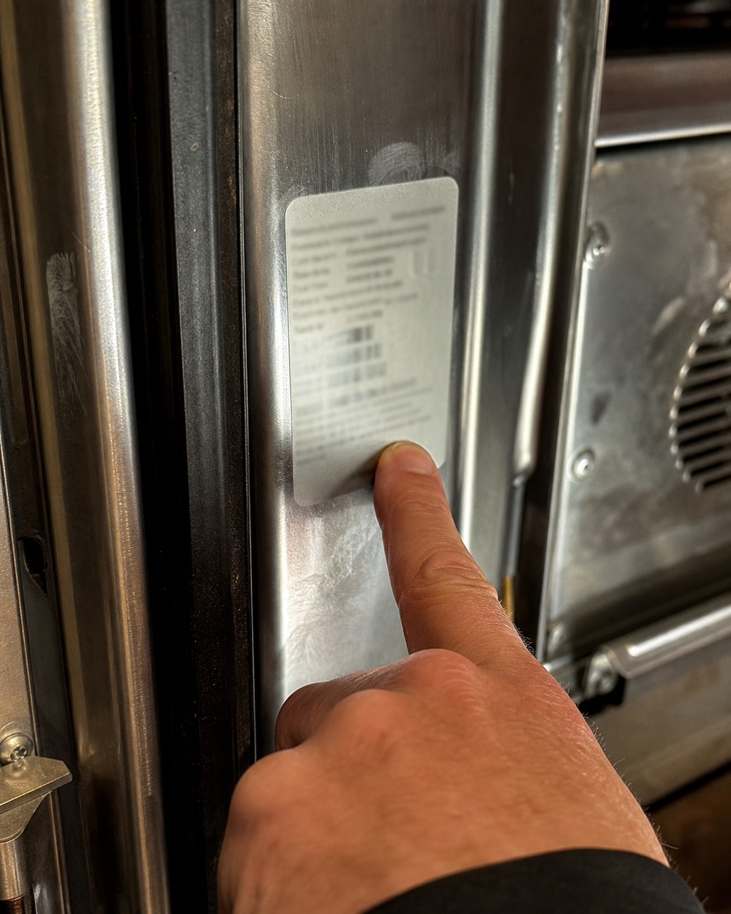 Close-up of a technician pointing to a Viking model and serial rating plate inside an appliance
